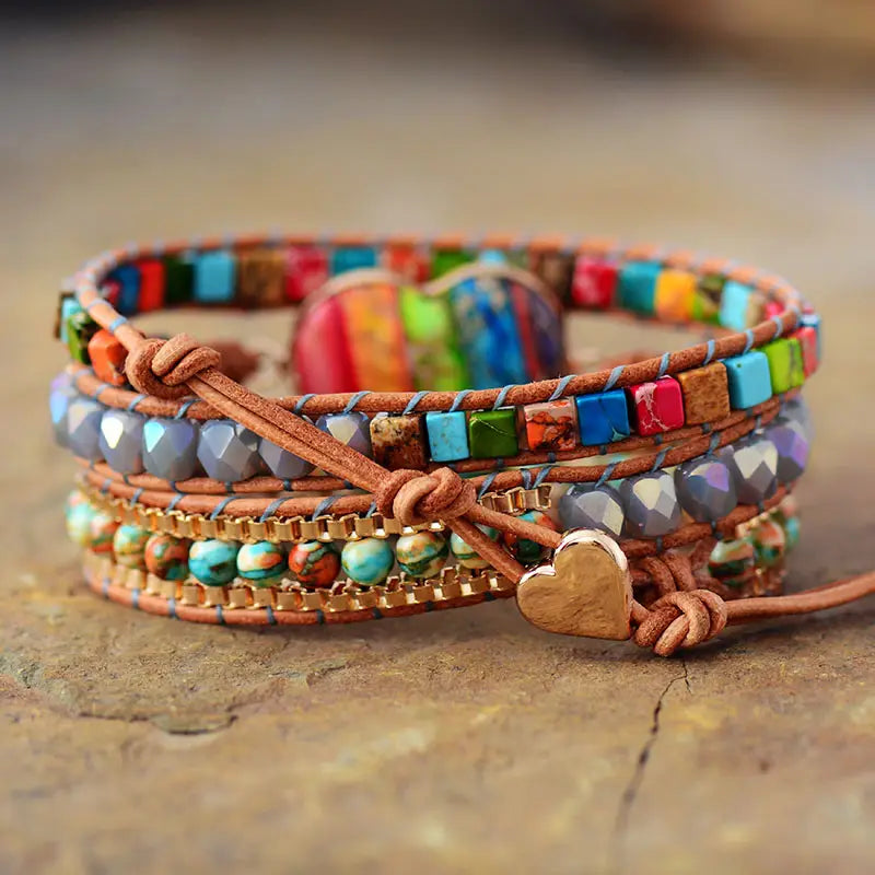 A multi-layered brown leather wrap bracelet featuring colorful turquoise red and blue beads metallic accents and a gold heart charm named rainbow heart imperial stone leather wrap bracelet.