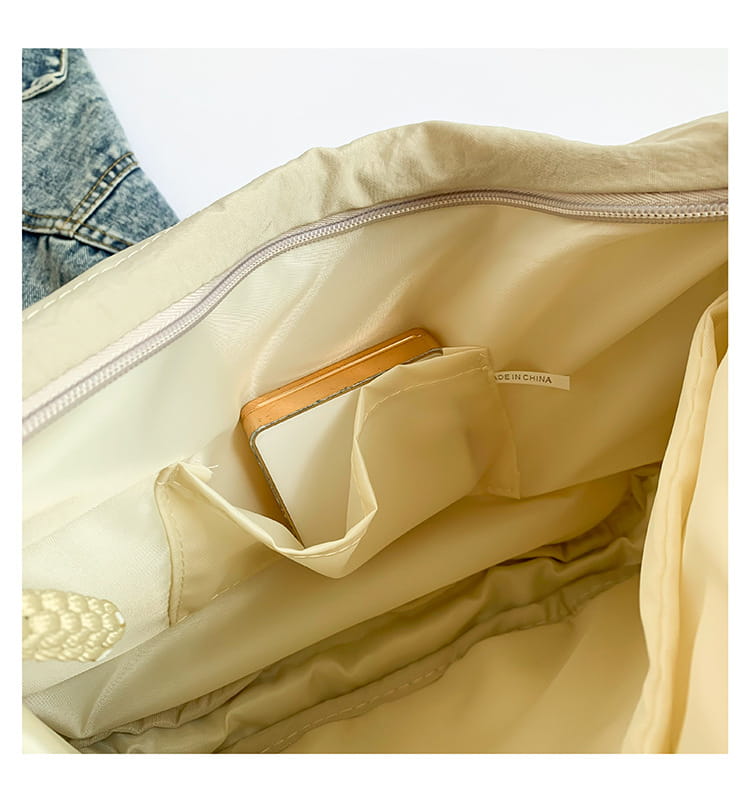 Beige nylon crossbody bag with a zipper closure and internal pocket holding a tan leather wallet designed as a large capacity hobo shoulder bag.