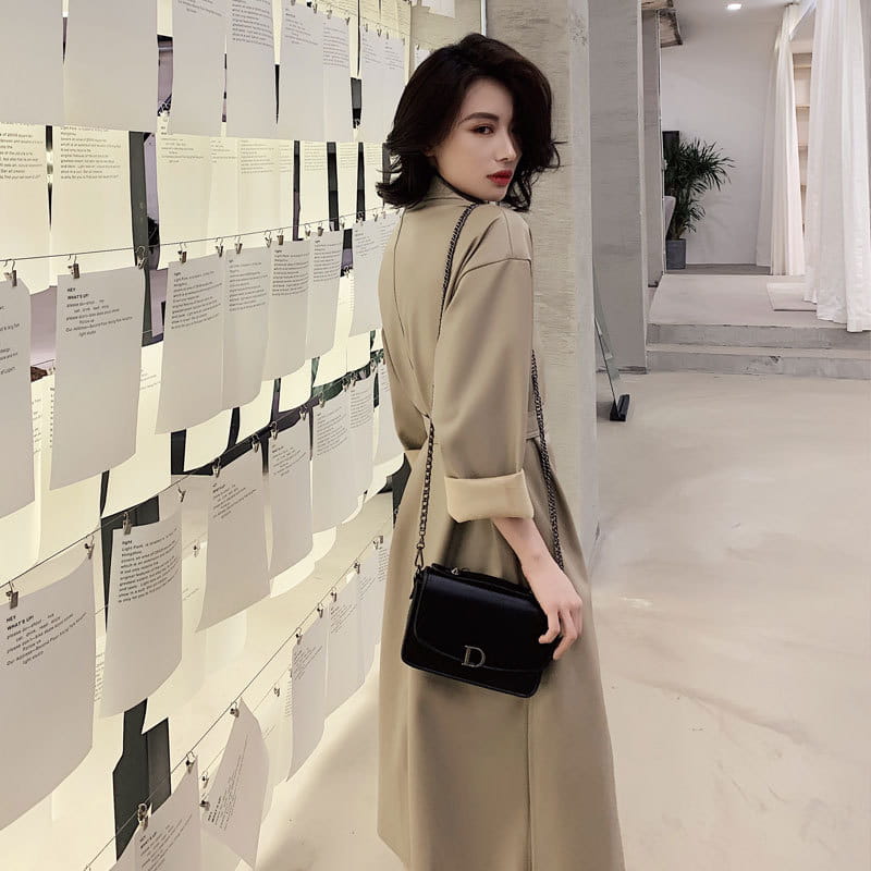 Black leather Dior handbag with gold chain strap paired with a faux leather trench coat belted long windbreaker jacket.