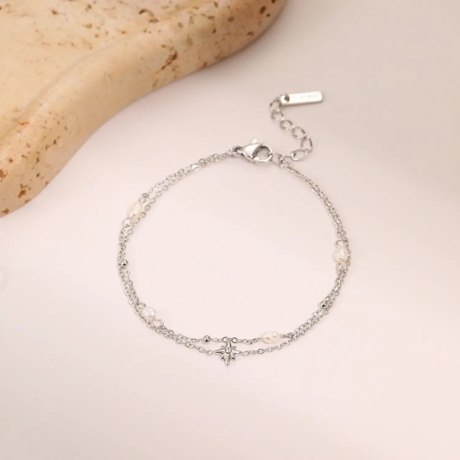 Silver double-strand bracelet with delicate chain links small white pearls and central star charm designed as a double layer 18k gold star and pearl stainless steel necklace.
