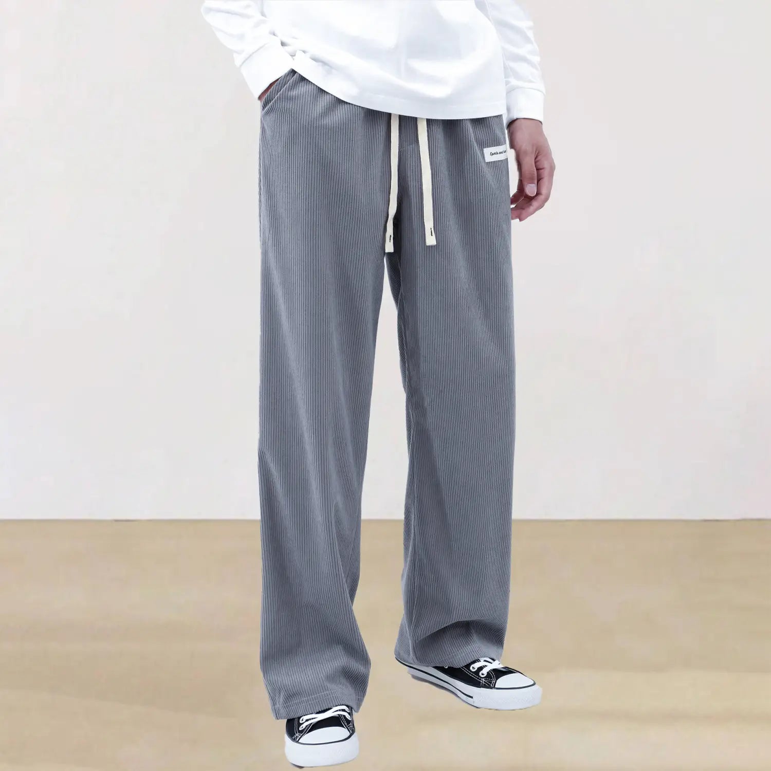 Men’s slim fit gray corduroy trousers with vertical stripes and a white drawstring waistband for casual sporty wear.