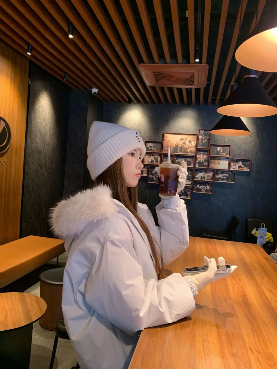 white puffer coat with a fluffy white fur-lined hood paired with a cat embroidered knitted beanie hat displayed on the front side.