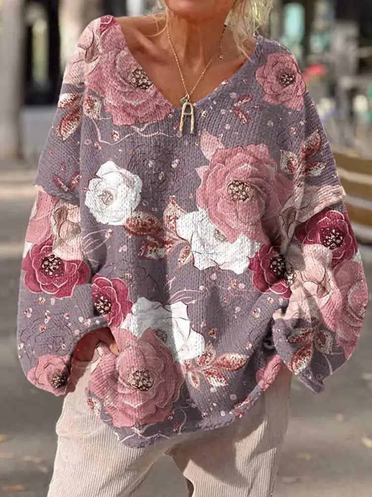 Un suéter esponjoso de punto gris suave y bordado de gato navideño, que presenta un patrón floral vibrante con rosas rosa y blancas, acentuadas con detalles brillantes.