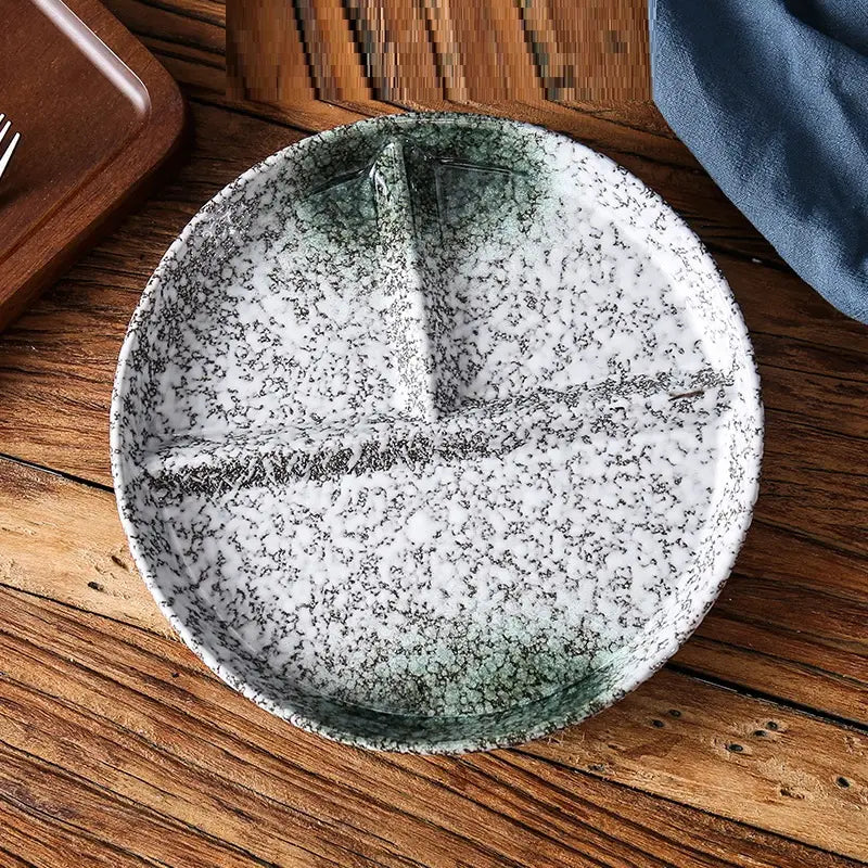 Service d’assiettes de dîner divisées en céramique blanche avec glaçure noire à mouchetures et rebord dégradé vert, comprenant trois sections séparées par des nervures en relief.