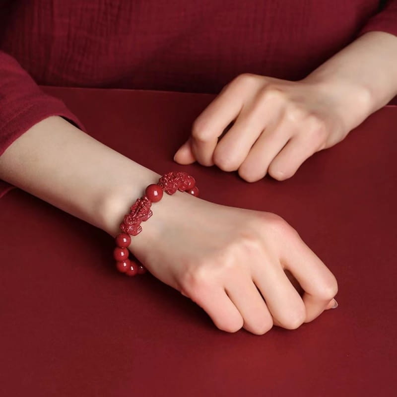 Hand carved purple gold cinnabar double pixiu bracelet featuring a red jade design with intricately carved dragon motifs and smooth polished beads.