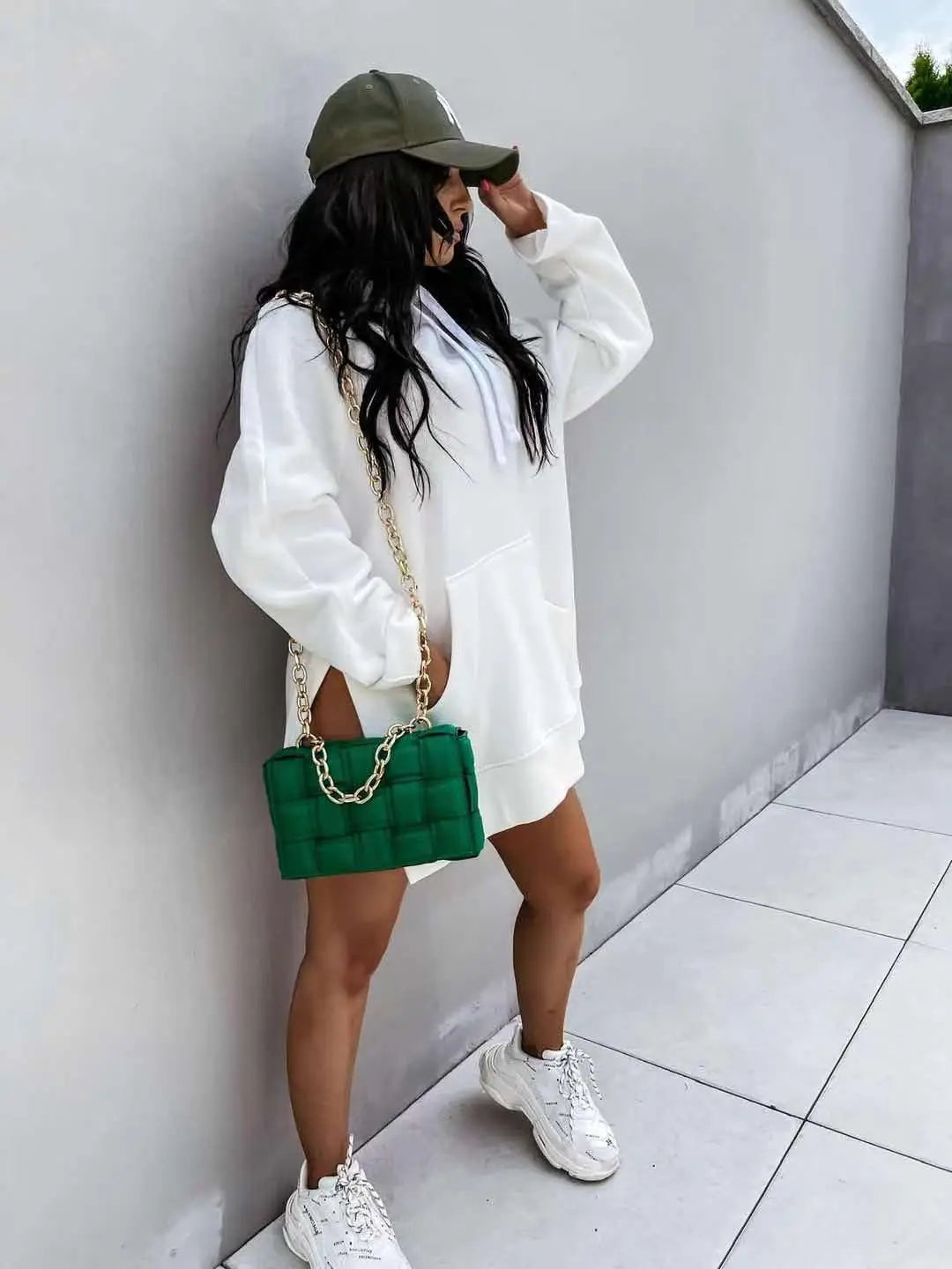 Green quilted chain strap handbag paired with oversized mid length hooded sweatshirt dress with pockets