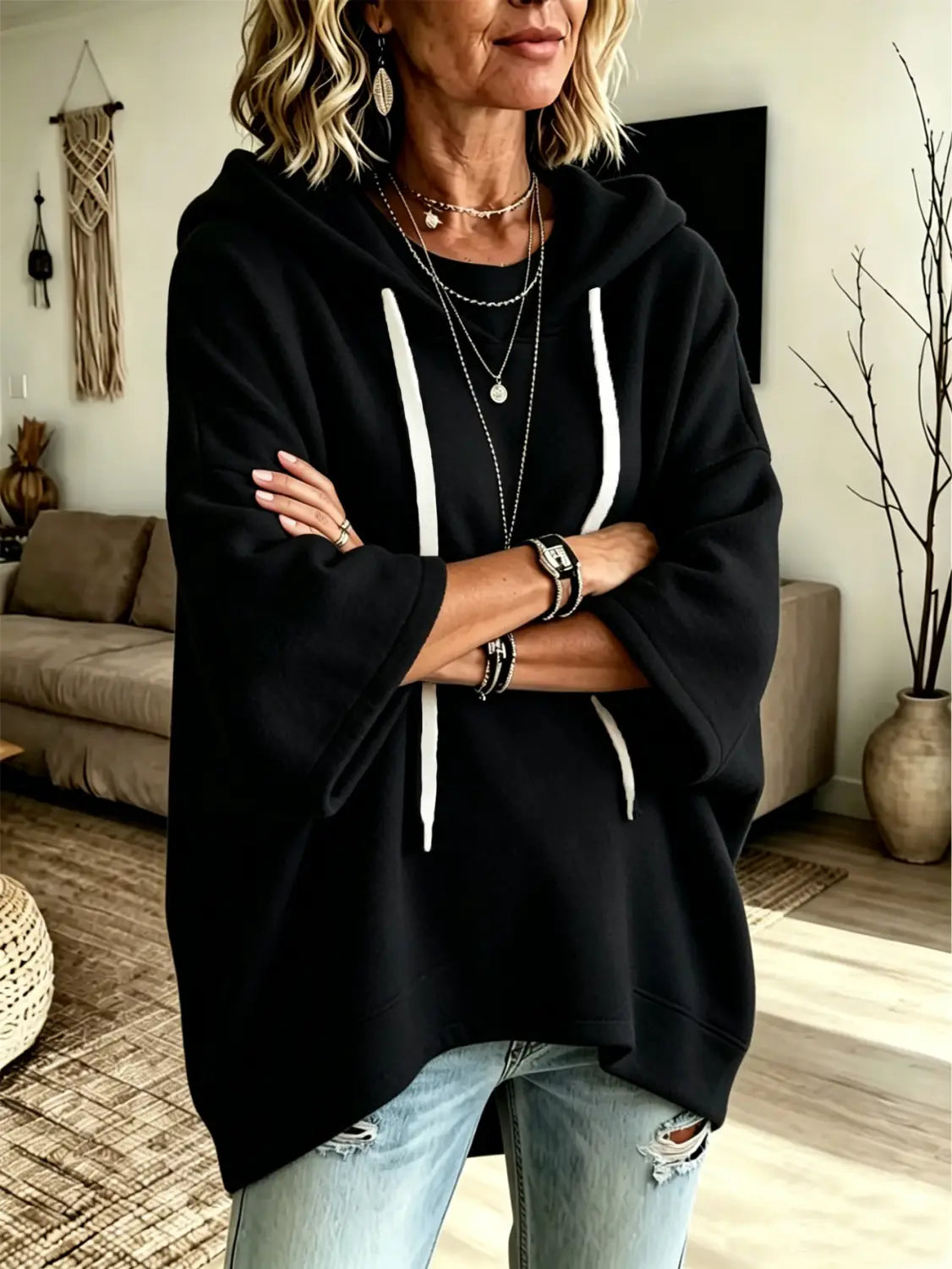 Black oversized fleece hooded top with three quarter sleeves and white drawstrings displayed from the front.