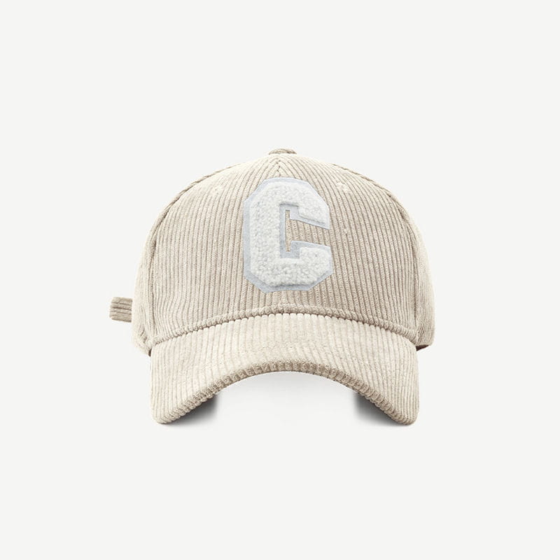 Beige corduroy baseball cap featuring a textured white embroidered c on the front.