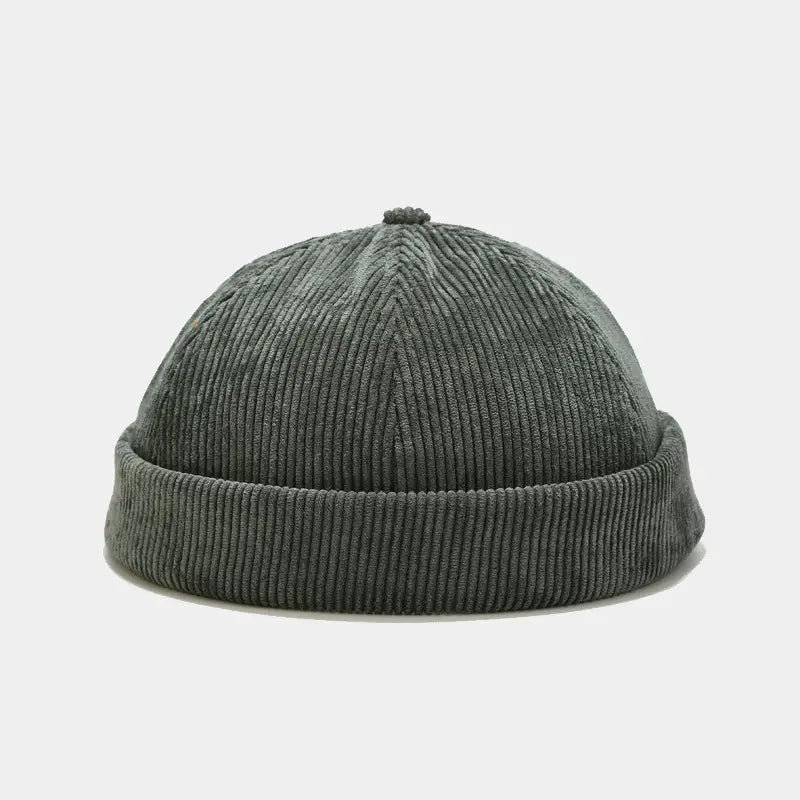 Dark green corduroy landlord beanie featuring a ribbed texture and folded brim designed as an adjustable streetwear hat.