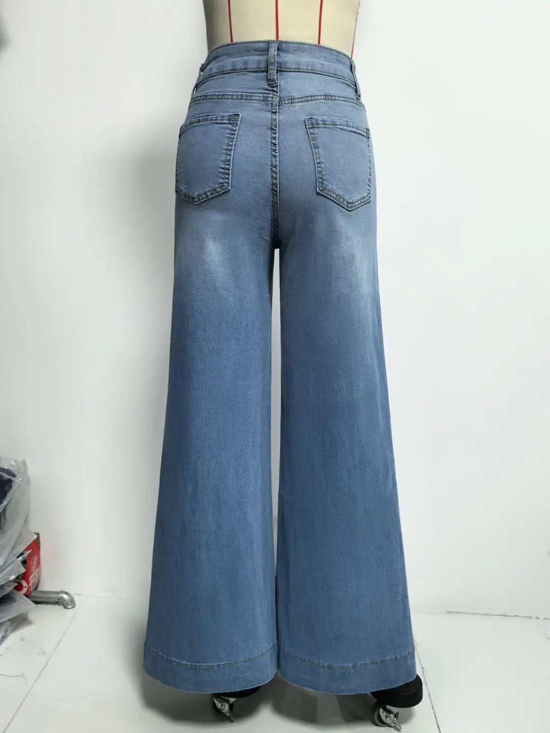 Die Rückseite heller Denim-Wide-Leg-Hochtaillenhosen mit klassischen Gesäßtaschen im Stil olivgrüner Denim-Jeans mit weitem Bein