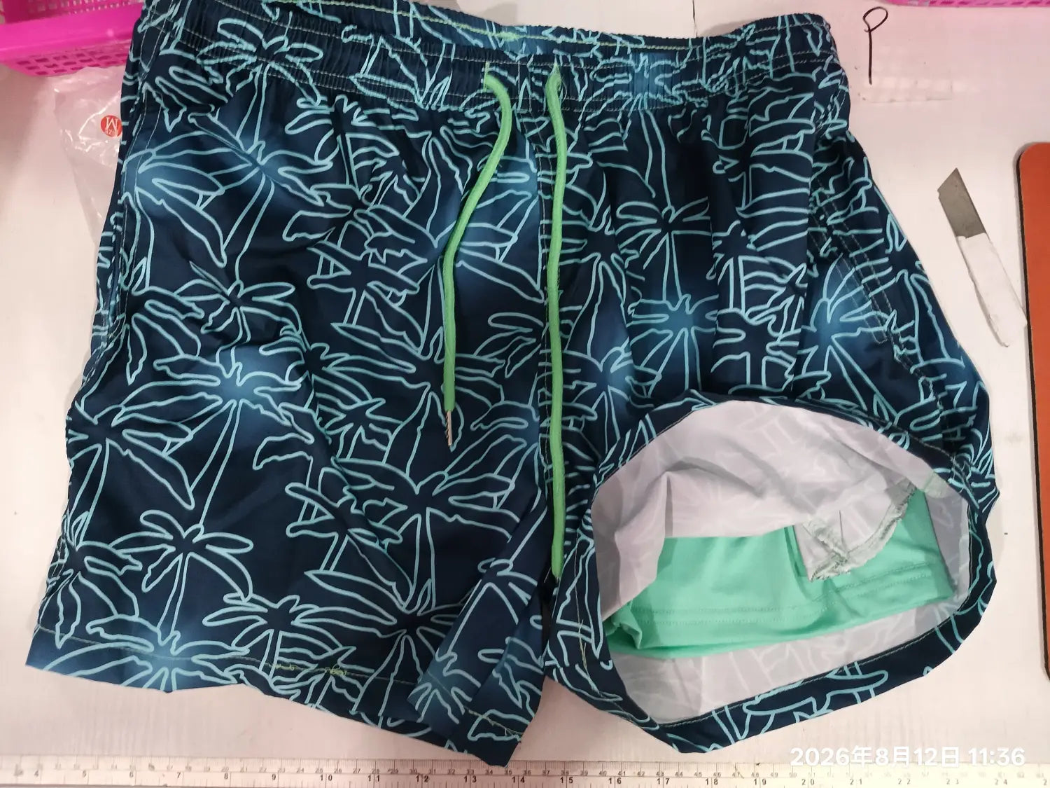 Dark blue printed men beach shorts featuring light teal palm tree outlines and lime green drawstrings designed for summer swim trunks.