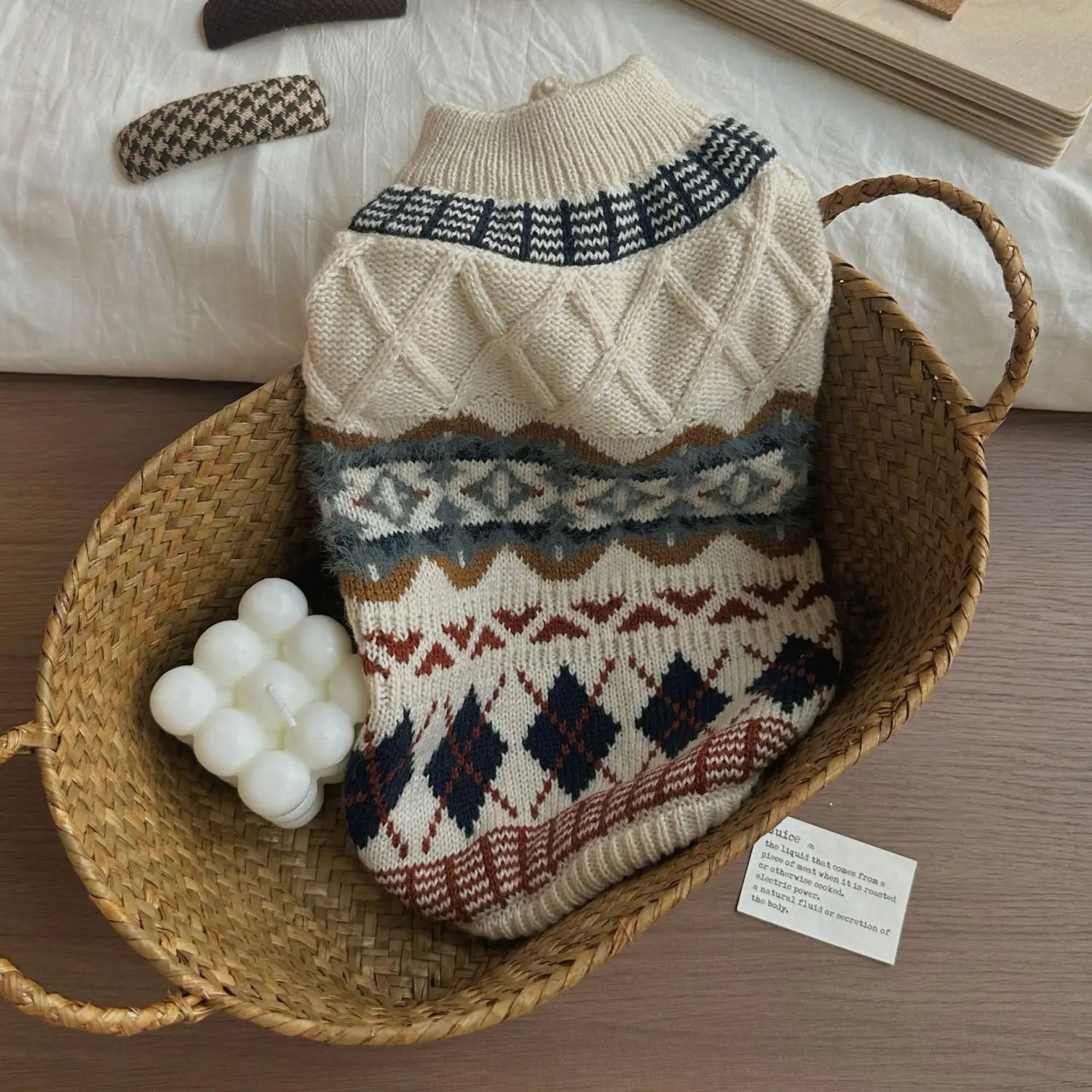 Pull pour chien tricoté couleur crème, orné de motifs géométriques vintage dans des tons marine, rouille et gris, conçu comme vêtement pour animal de compagnie.