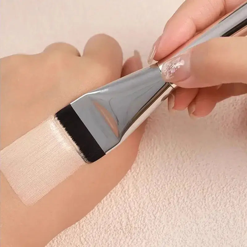 A sleek metallic silver ultra thin foundation brush with a black rubberized edge and soft white bristles for flat traceless makeup application.