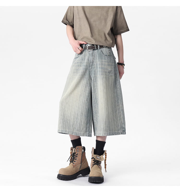 striped denim capri shorts featuring wide-leg cut with faded vertical stripes and distressed details on blue denim fabric.