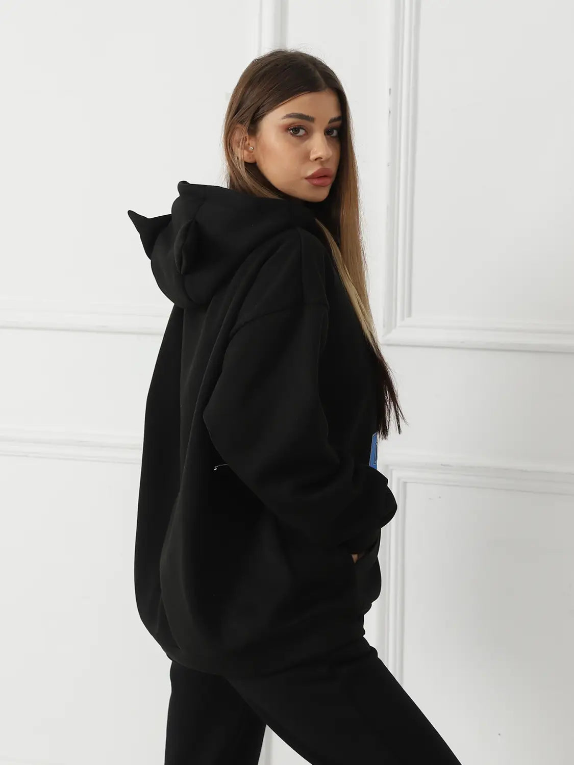 Black oversized women’s dalmatian print hoodie made of soft material with a hood featuring cat ear-like cutouts shown from the back side.