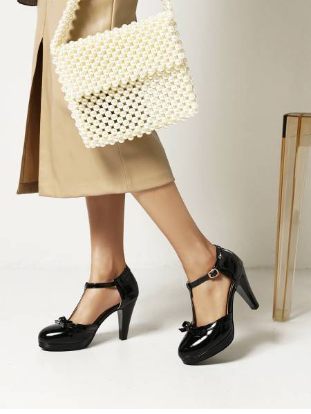 Black patent leather platform high heels with a t-strap design and small bow accents.