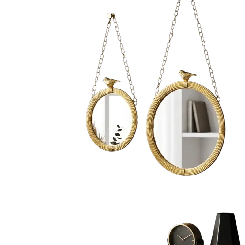 Two oval decorative mirrour with gold-toned resin frame and bird finials hanging on dark interior wall