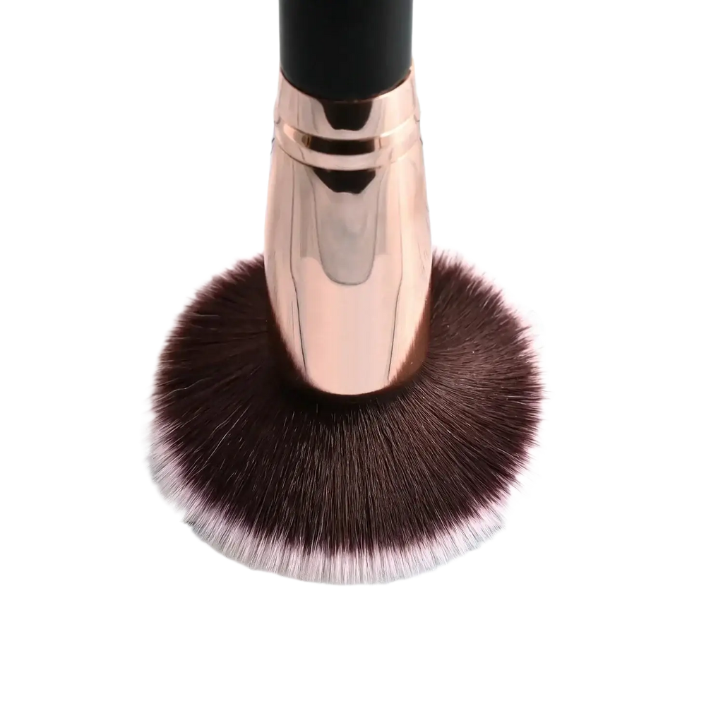 Rose gold finished makeup brush with dense dark brown bristles tipped in soft pink shown with deep blue essential oil blend 120 ml tube