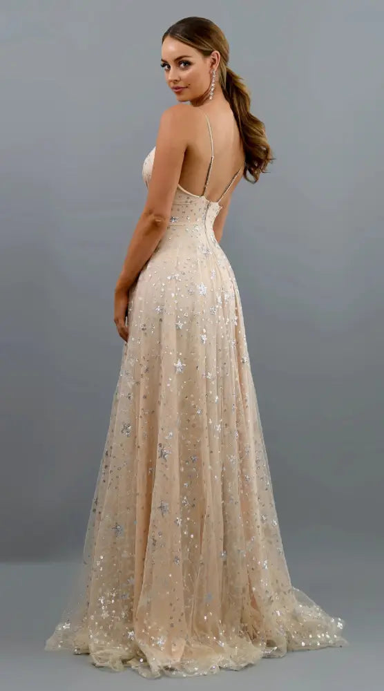 A flowing champagne-colored star embellished deep v slit evening gown with a fitted bodice and delicate silver accents