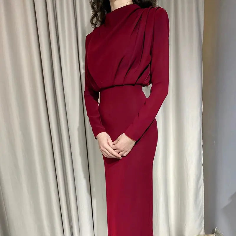Une robe longue maxi à col montant structurée à manches longues, élégante, rouge profond, avec un décolleté drapé et une silhouette ajustée.