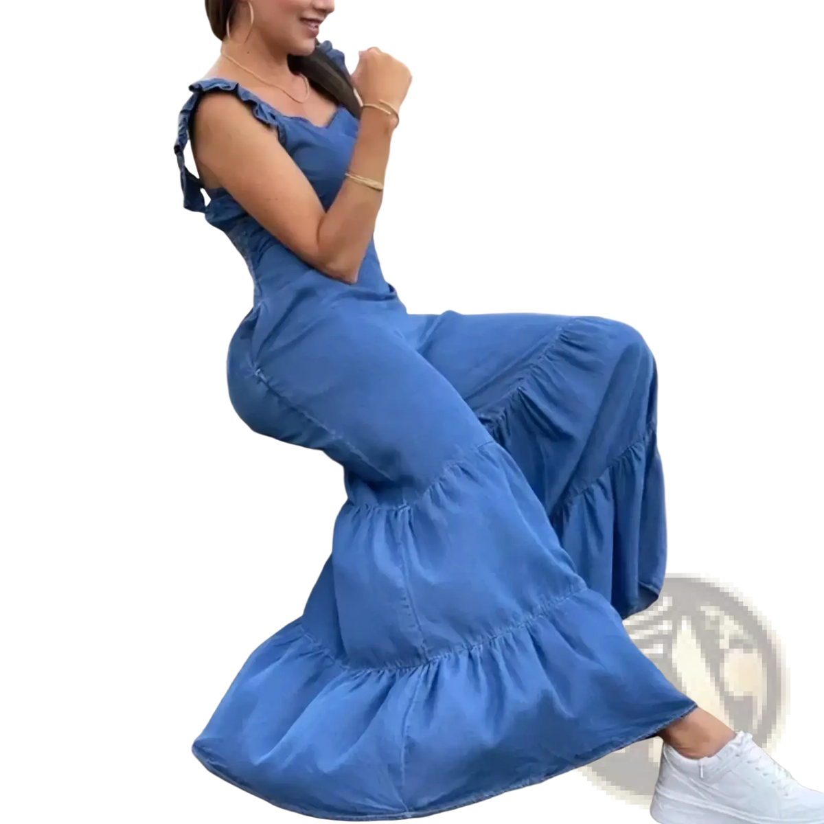 A woman wearing a blue denim ruffled flare jumpsuit with shoulder straps and a tiered hem