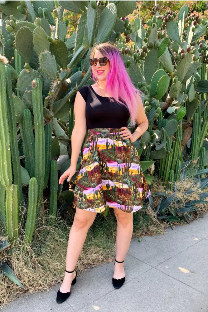 A vibrant multicolored cotton a line skirt featuring a desert cactus landscape print in pink purple and green hues