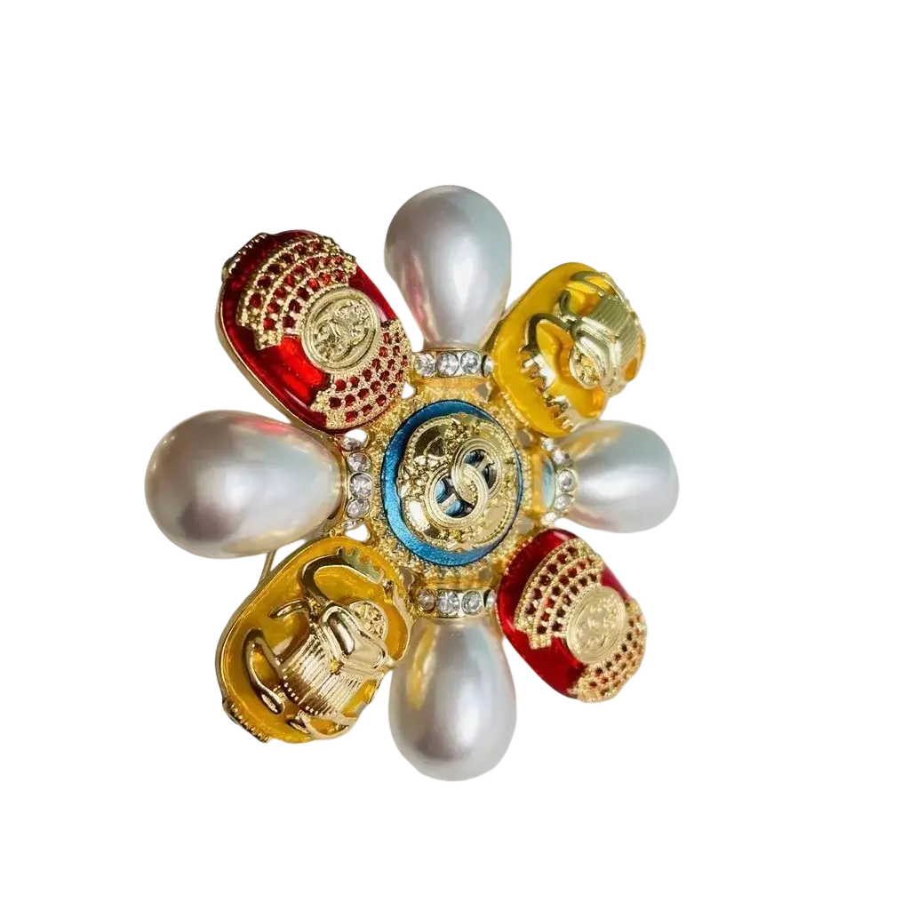 A vibrant flower-shaped Chanel brooch with red and gold enamel petals, pearls, crystals, and a central blue medallion
