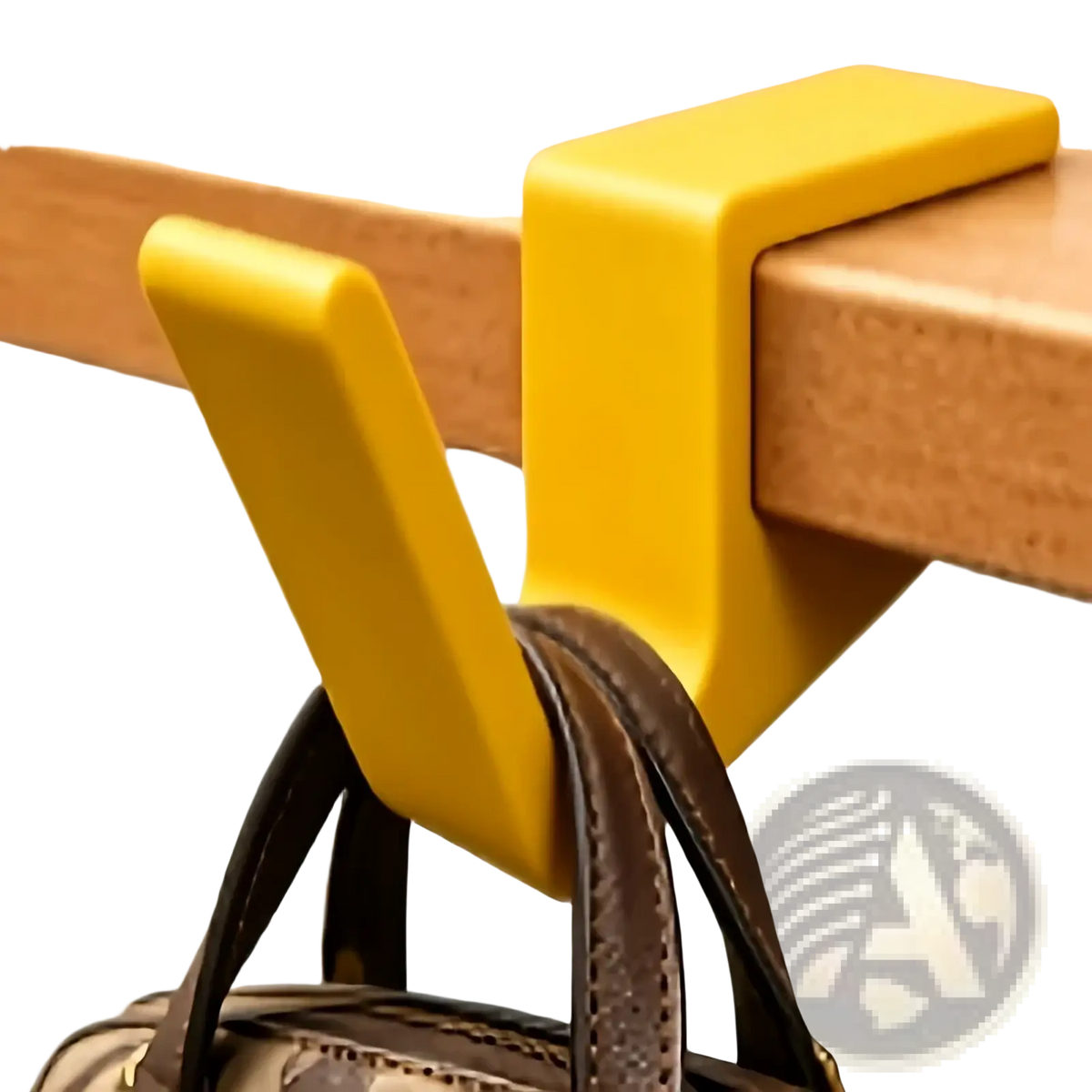 Bright yellow plastic desk edge bag hook holding a brown leather bag strap for backpack or handbag storage