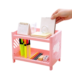 Pink two-tier plastic desk organizer with slotted sides and grid-patterned bottom shelf for efficient storage