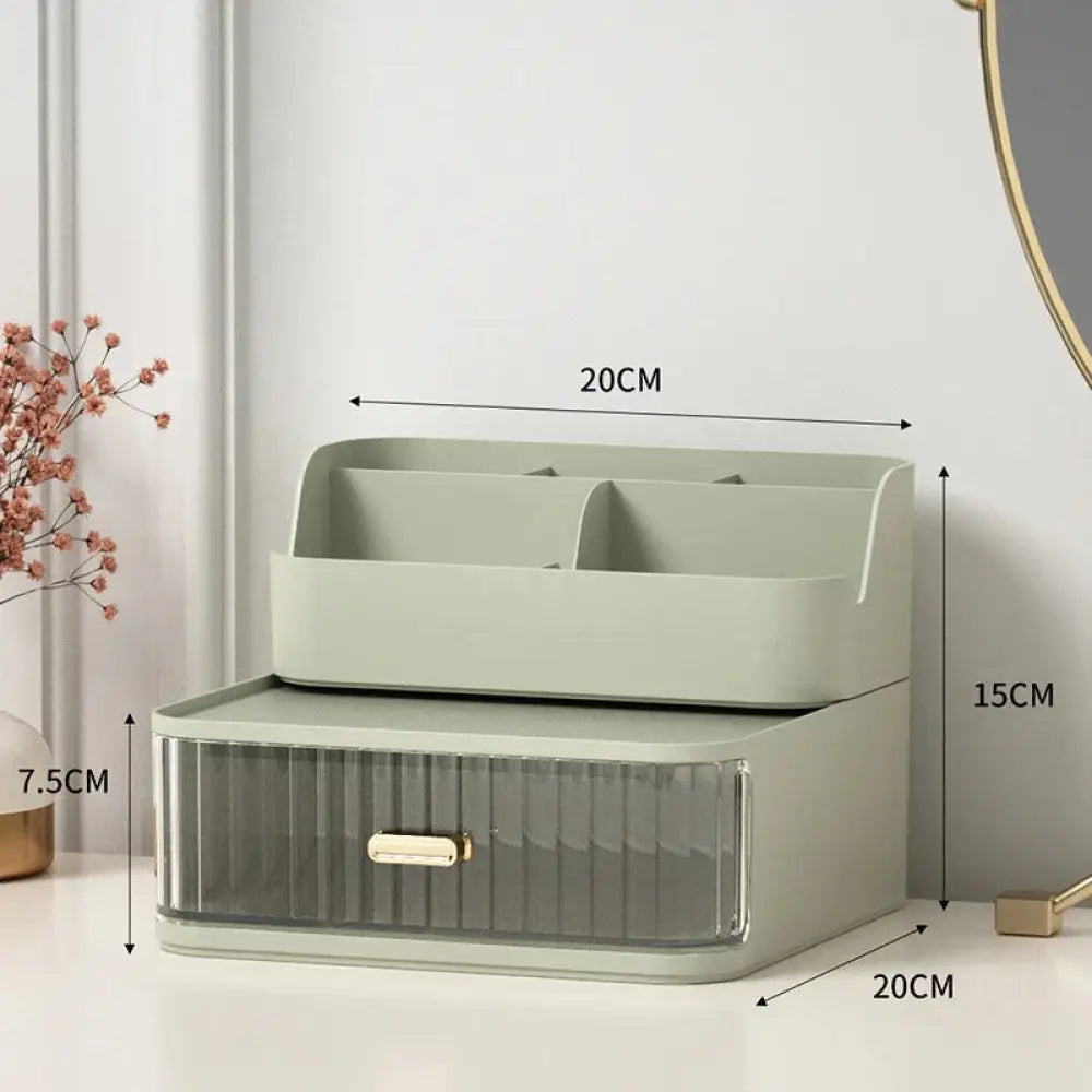 A sleek sage green two tiered desktop makeup and jewelry organizer with a translucent ridged drawer and gold handle