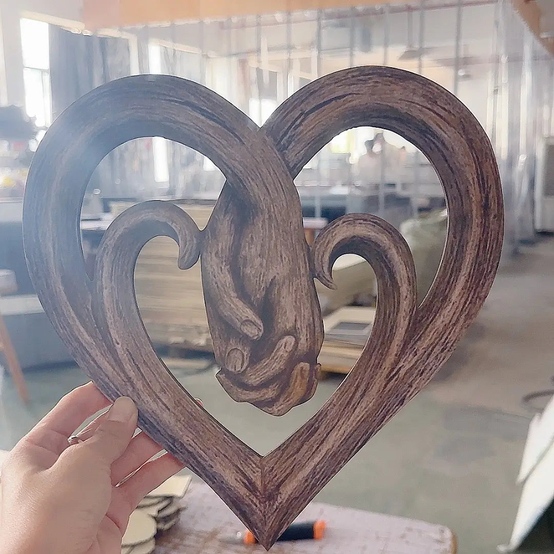 Rustikale herzförmige Wanddekoration aus dunkelbraunem Holz mit einem geschnitzten Widderkopf-Design als dekoratives Element.