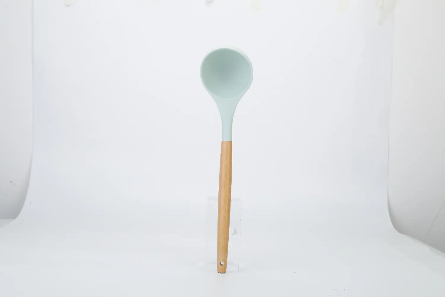 a sleek light blue silicone ladle with a natural wood handle from an 11 piece silicone cooking utensil set with wood handles