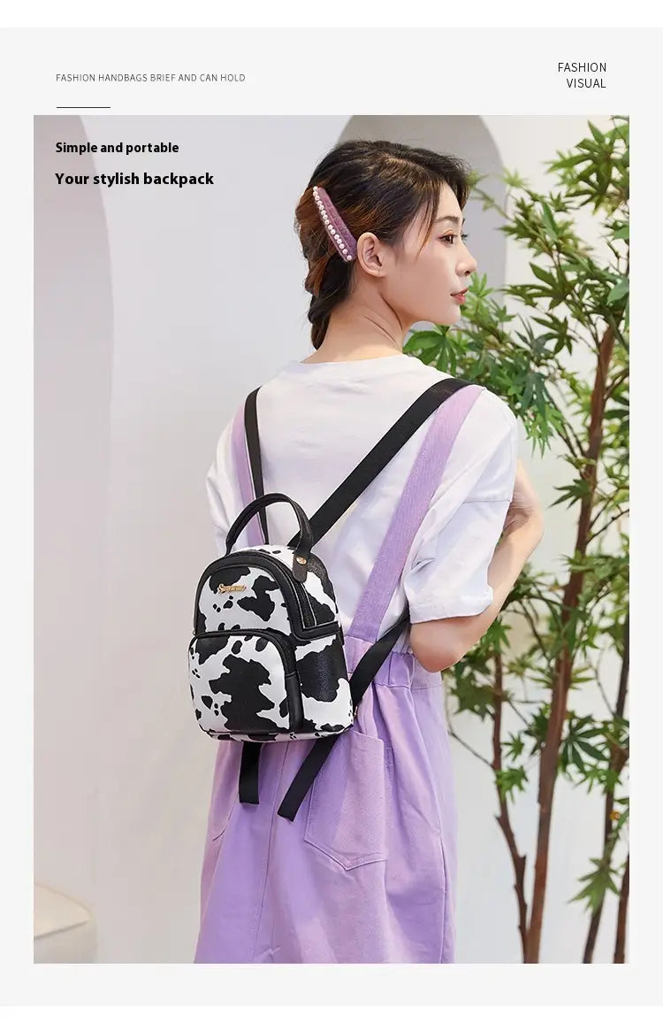 mini backpack cow and snake print korean style featuring black and white cow print design with black straps shown from the front.