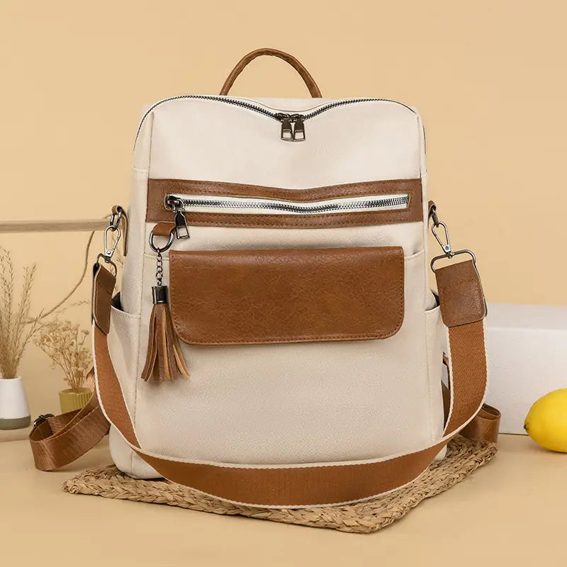 One shoulder cream and brown faux leather backpack with front zipper pocket tassel detail and adjustable shoulder straps measuring 35cm.