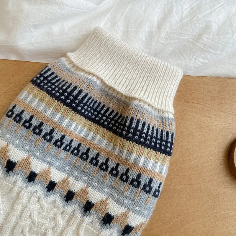 Ein gemütlicher Hundepullover in cremefarbener Strickoptik mit hohem geripptem Kragen und aufwendigen navyblauen, beigen, grauen und weißen geometrischen Mustern aus weichem Strick im Stil Fair-Isle-Blau für Heimtierbedarf.
