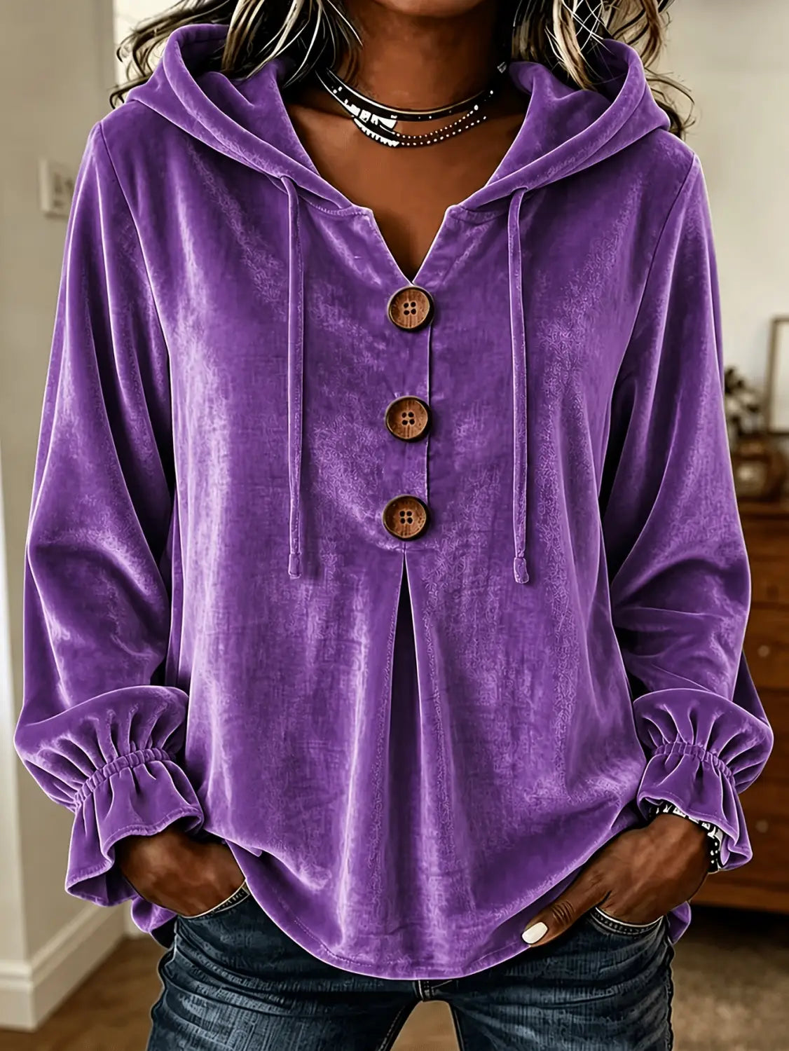 Sudadera de terciopelo morada con botones de madera y puños fruncidos, exhibida de frente, mostrando su material suave y su diseño elegante.