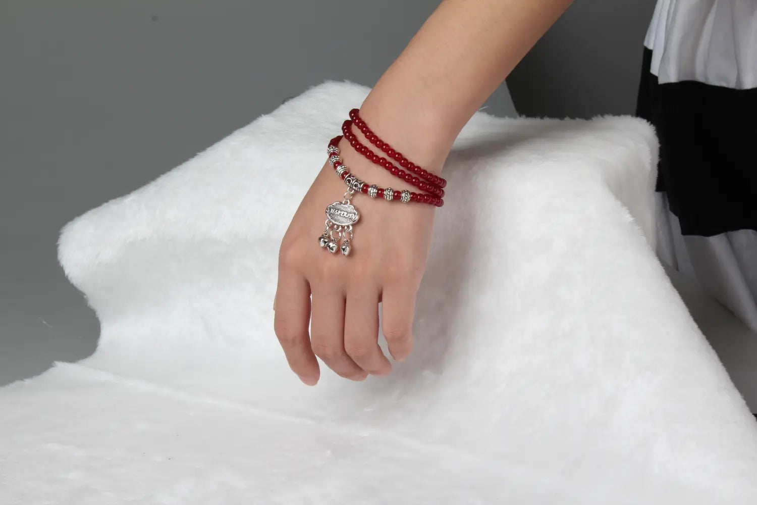 red agate good luck bracelet featuring red beads with a silver-toned engraved protect charm and small bells.