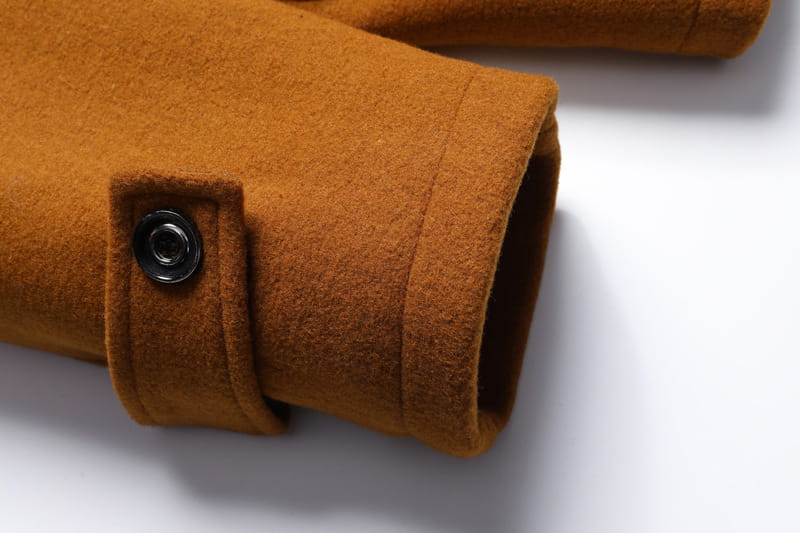 Warm brown wool cuff with a black snap button on a men wool winter overcoat quilted jacket.