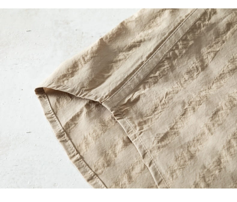 Beiger Leinenstoff mit sichtbarer Naht und natürlicher Textur auf einem gestreiften kurzärmligen Casual-Shirt