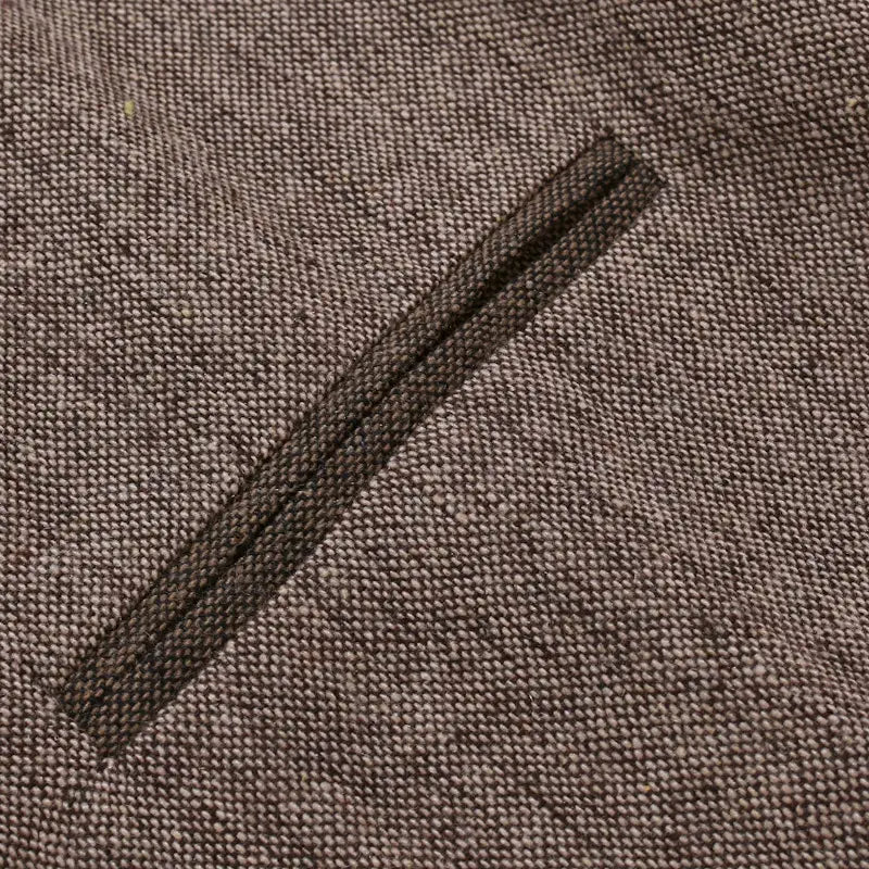 Ein dunkelbrauner Reißverschluss, eingearbeitet in einen strukturierten Webstoff, an einer Herren-Tweedweste im Slim-Fit im Business-Casual-Stil.