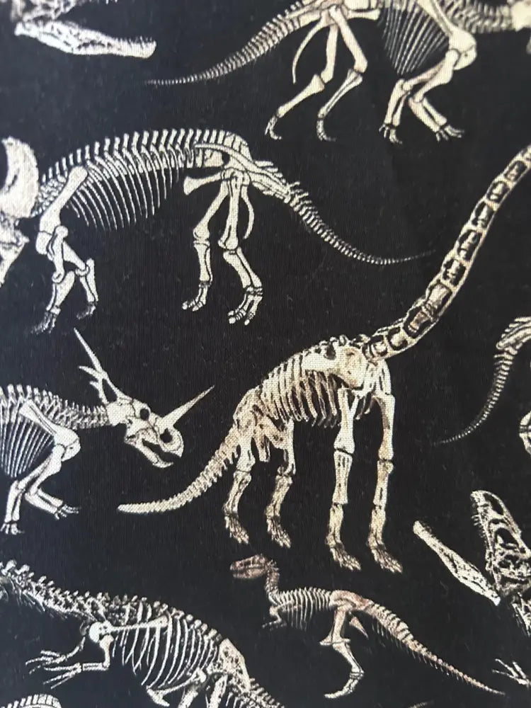Black vintage cotton skater skirt with a repeating pattern of white and beige dinosaur skeletons in various poses
