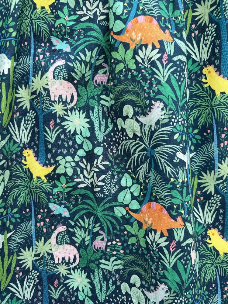 Dark blue cotton fit and flare dress with pockets featuring vibrant cartoon orange yellow and pink dinosaur jungle print