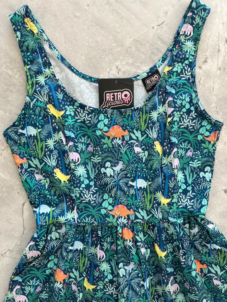 A vibrant teal cotton sleeveless fit and flare dress with pockets featuring a playful dinosaur and jungle foliage print