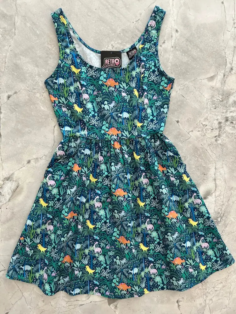 A vibrant teal cotton fit and flare sleeveless dress with colorful dinosaur and tropical foliage pattern and pockets