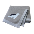 Gray knitted cotton baby blanket featuring a white and black dinosaur design with ribbed edges for crib use