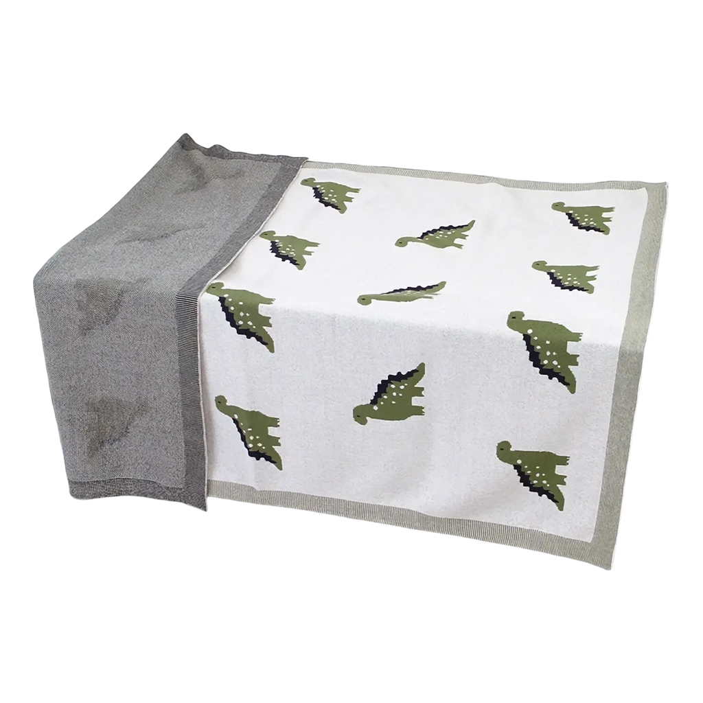 A soft white cotton dinosaur knit baby blanket with green prints and a gray border for crib use