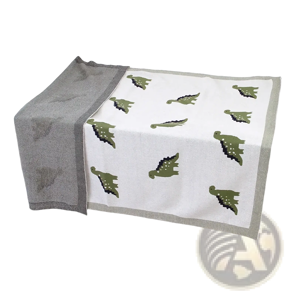 A soft white cotton dinosaur knit baby blanket with green prints and a gray border for crib use