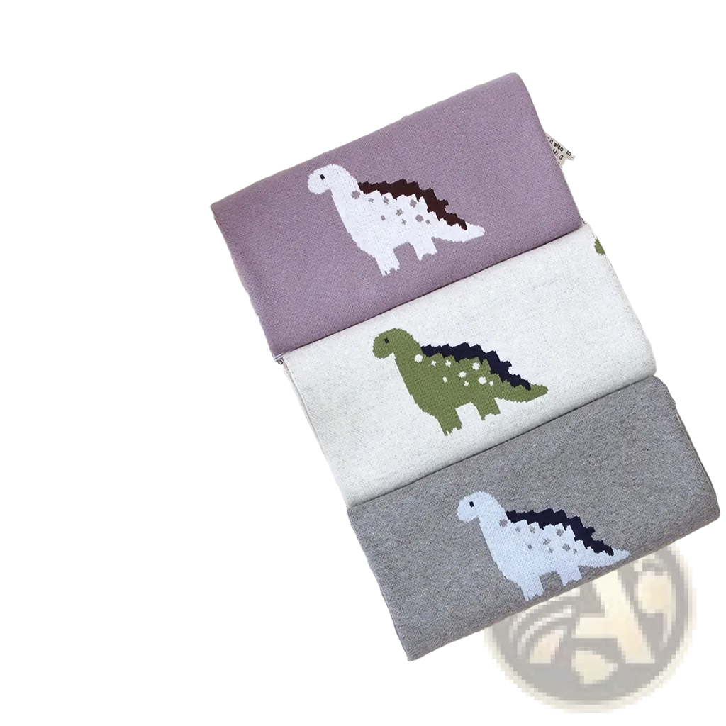 Three pairs of soft knitted cotton children’s socks in muted purple off-white and gray with dinosaur designs