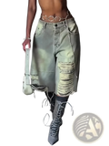 Distressed cropped denim pants in light-wash denim with ripped and frayed detailing styled with a chain belt and boots