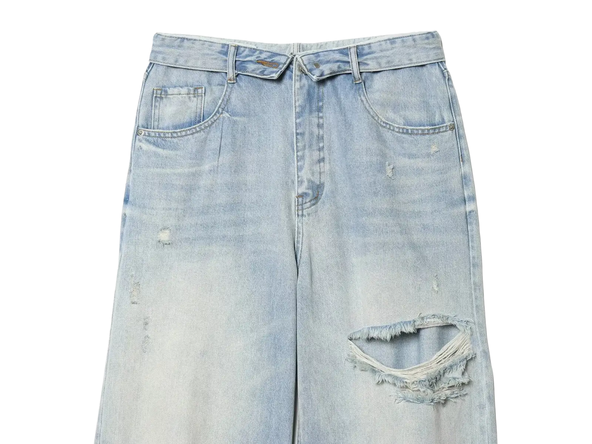 Distressed mid waist wide leg denim jeans in light wash with frayed holes and subtle fading on cotton fabric